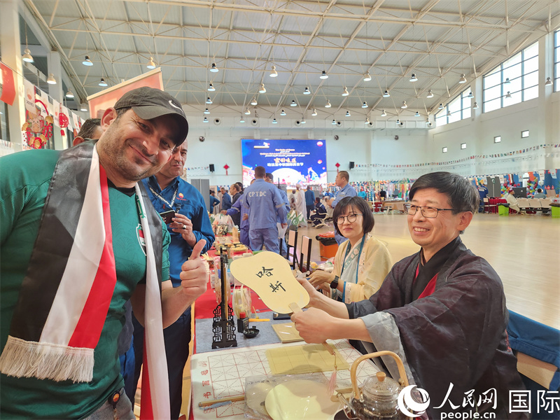 图为一名伊拉克员工高兴地接过一把写有自己中文名字的扇子。 人民网记者 管克江摄