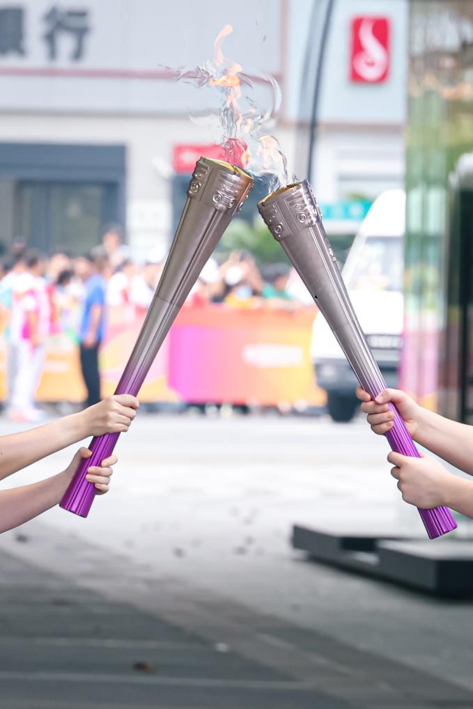 　　2023年9月8日，亚运火炬手在火炬传递中交接。新华社记者 江汉 摄